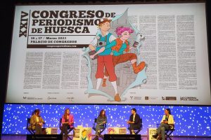 Escenario del Palacio de Congresos de Huesca con los ponentes de la mesa de debate sobre información en TikTok