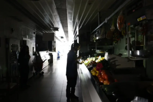 Una mujer mirando unas frutas y verduras con su linterna del móvil a oscuras