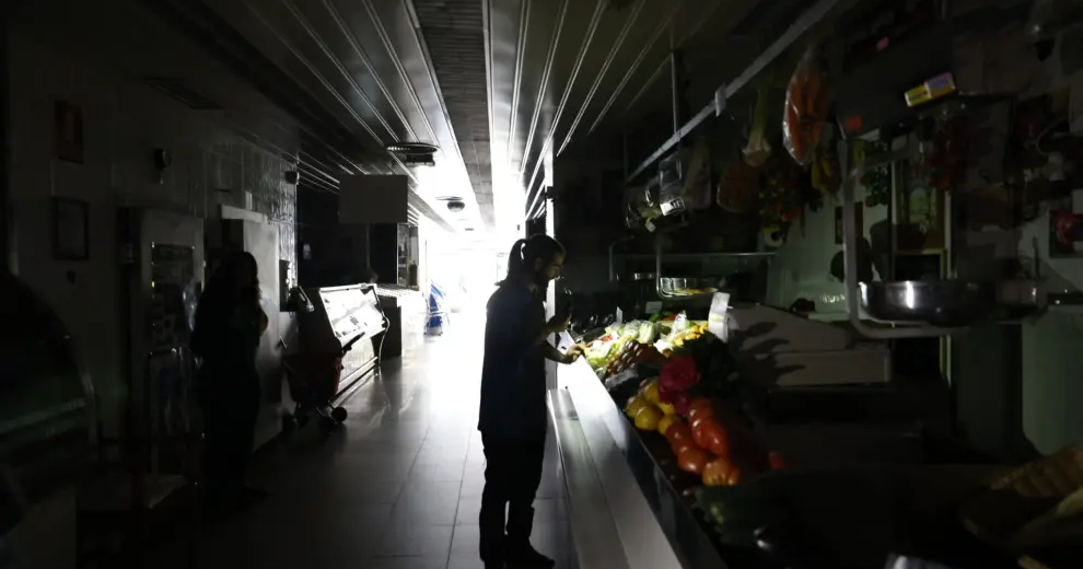Una mujer mirando unas frutas y verduras con su linterna del móvil a oscuras