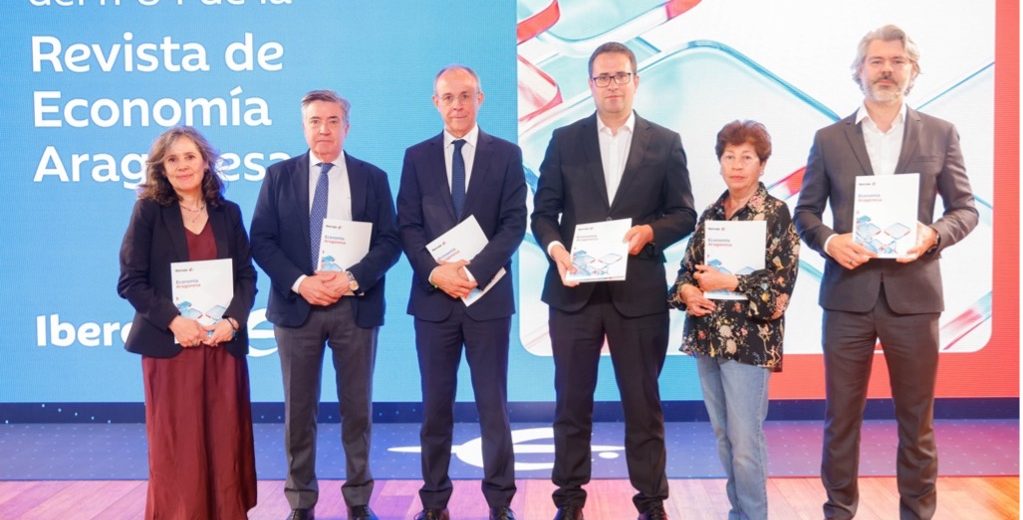 Seis personas posan en el escenario durante la presentación del número 84 de la Revista de Economía Aragonesa, organizada por Ibercaja. Cada una sostiene un ejemplar de la revista frente a un fondo azul con el nombre del evento.